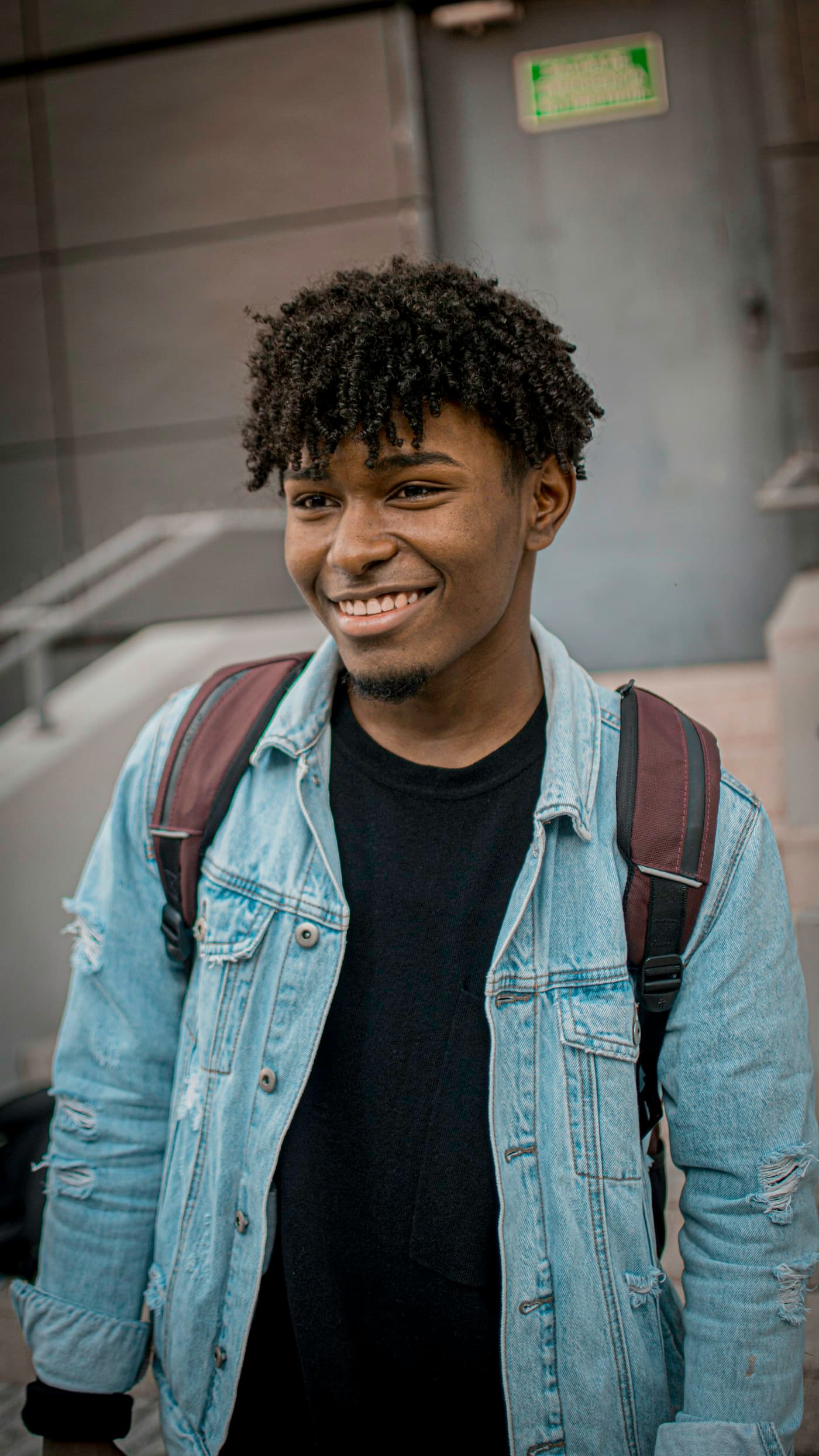A smiling student with a backpack, looking ahead to his next chapter
