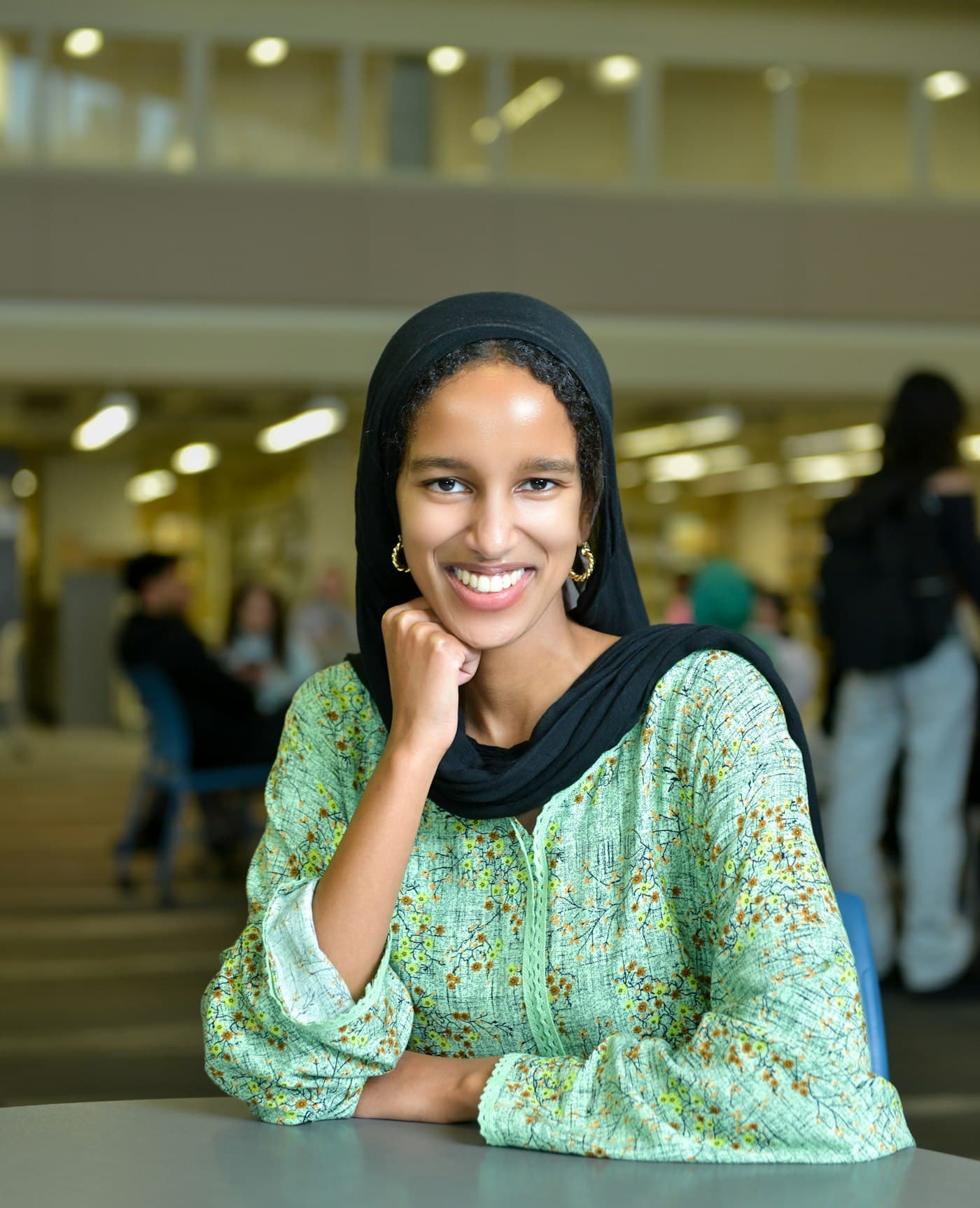 A smiling student at a library table, planning her next step